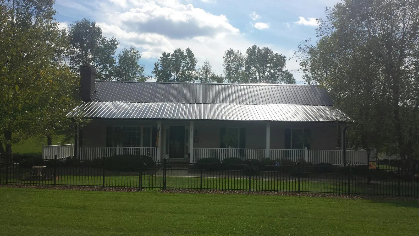Gray metal roof on a brick ranch with a full width front porch — Gutter Guard Installation work by our crew in Northport