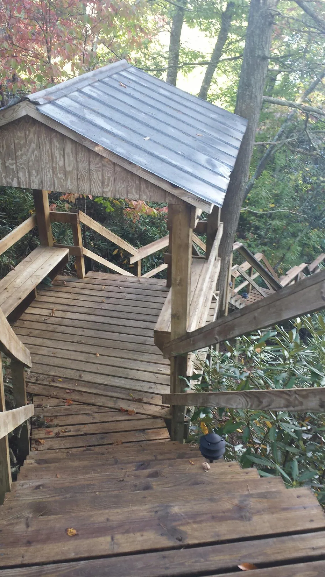 Metal roofed shelter over wooden steps on a wooded walkway — Skylight Repair & Installation work by our crew in Northport