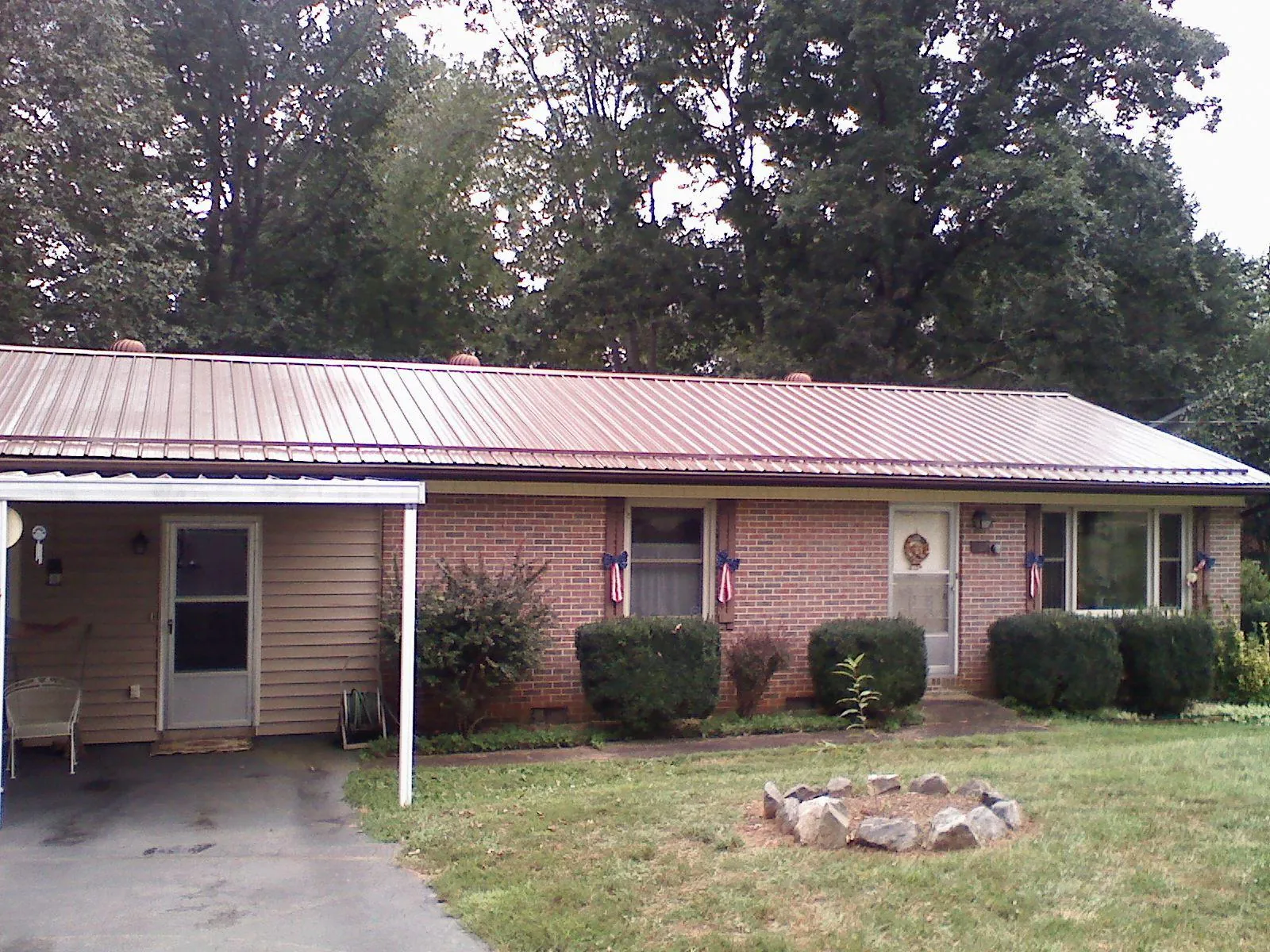 Bronze metal roof and carport on a brick ranch home — Roof Repair work by our crew in Northport